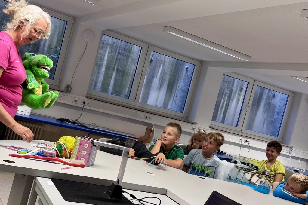 Frau Hohmann zeigt den Kindern mit einem Krokodil-Handpuppe das richtige Zähneputzen
